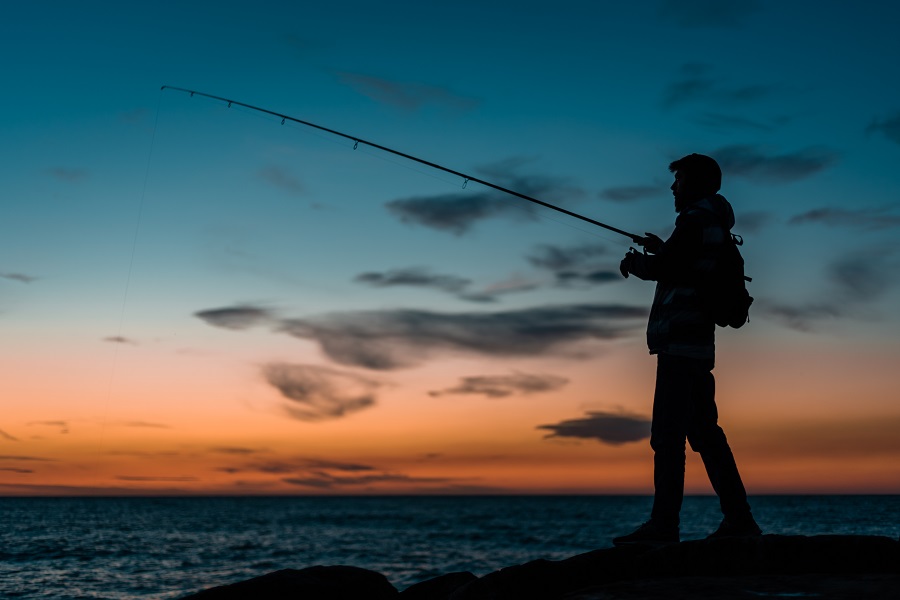 sagoma-di-un-uomo-che-pesca-in-spiaggia-al-tramonto
